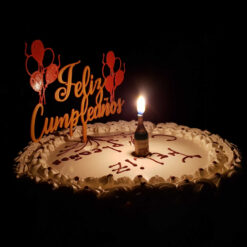 Cake topper en la torta de cumpleaños, con la luz apagada y una vela encendida - Feliz cumpleaños.